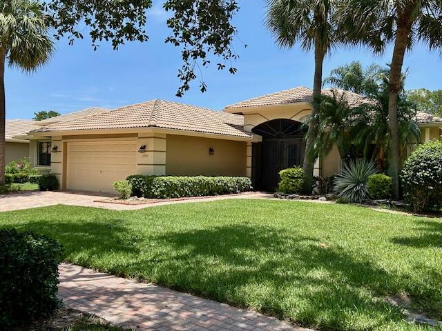 11090 Via Amalfi, Boynton Beach, FL 33437 - mediterranean / spanish home featuring a garage, a front lawn, and stucco siding
