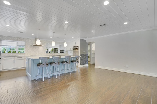 4040 Gem Lake Dr, Glen Ridge, FL 33406 - kitchen with a kitchen bar, white cabinets, backsplash, light countertops, and a spacious island