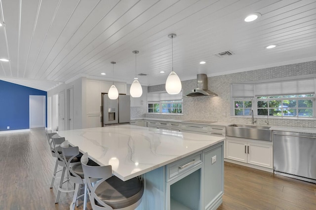 4040 Gem Lake Dr, Glen Ridge, FL 33406 - kitchen featuring stainless steel appliances, wall chimney range hood, a sink, ornamental molding, and white cabinetry