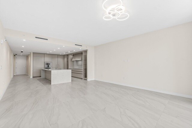 220 SE Mizner Blvd Unit 409, Boca Raton, FL 33432 - unfurnished living room featuring a sink, baseboards, light marble finish flooring, and recessed lighting
