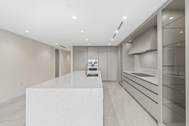 220 SE Mizner Blvd Unit 409, Boca Raton, FL 33432 - kitchen with modern cabinets, gray cabinetry, wall chimney exhaust hood, a sink, and a large island with sink