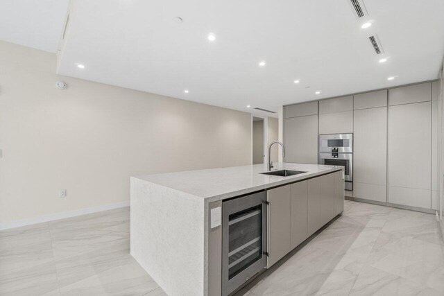 220 SE Mizner Blvd Unit 409, Boca Raton, FL 33432 - kitchen with beverage cooler, a sink, modern cabinets, gray cabinetry, and light marble finish floors