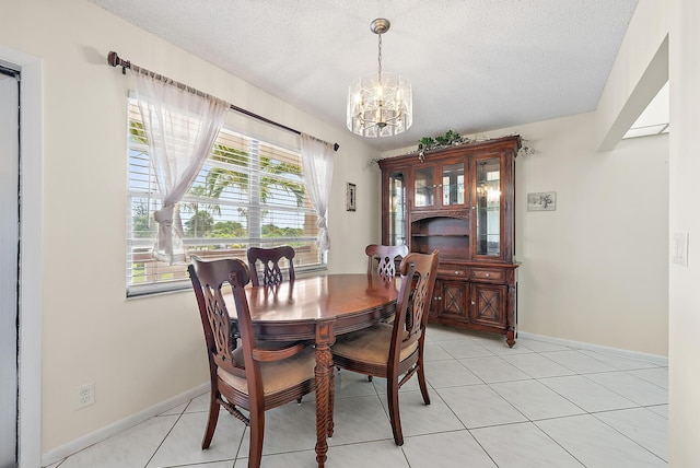 222 Wellington Unit G, West Palm Beach, FL 33417 - dining space featuring a chandelier, a textured ceiling, light tile patterned flooring, and baseboards