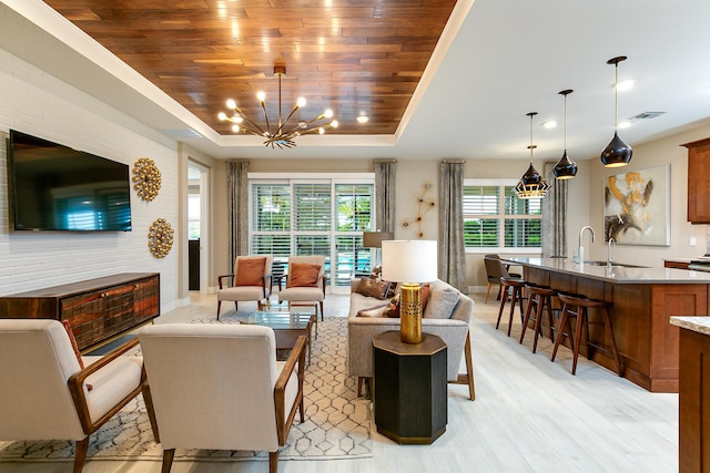 17155 SW Ambrose Way, Port Saint Lucie, FL 34986 - living room featuring a tray ceiling, wood ceiling, a chandelier, light wood-type flooring, and baseboards