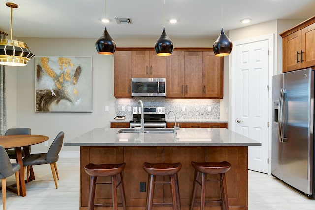17155 SW Ambrose Way, Port Saint Lucie, FL 34986 - kitchen with stainless steel appliances, light wood-style flooring, a sink, backsplash, and brown cabinets
