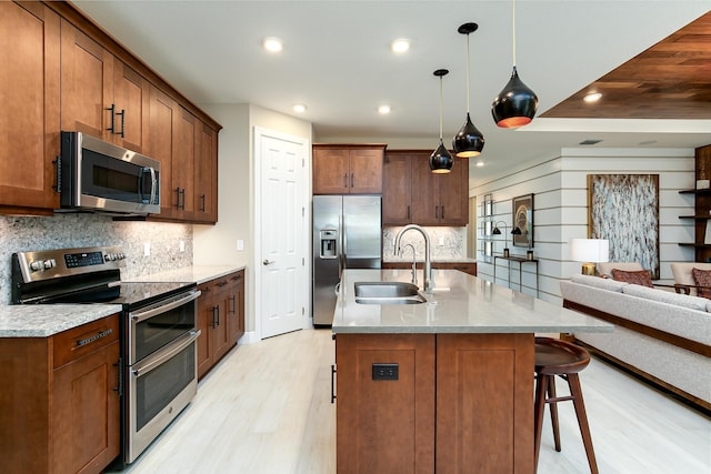 17155 SW Ambrose Way, Port Saint Lucie, FL 34986 - kitchen with appliances with stainless steel finishes, a sink, light wood-style floors, open floor plan, and a breakfast bar