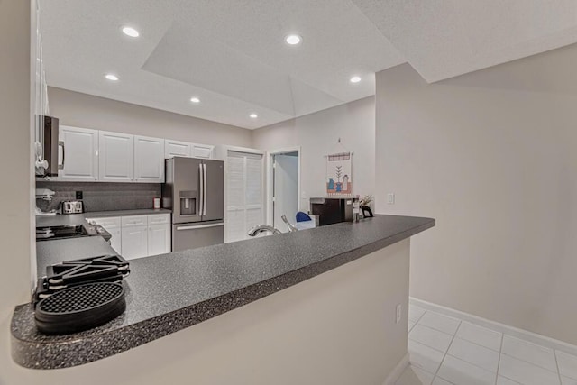 9998 Seacrest Cir Unit C, Boynton Beach, FL 33437 - kitchen featuring stainless steel appliances, dark countertops, light tile patterned floors, baseboards, and a peninsula