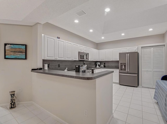 9998 Seacrest Cir Unit C, Boynton Beach, FL 33437 - kitchen with stainless steel appliances, a peninsula, dark countertops, light tile patterned floors, and white cabinets