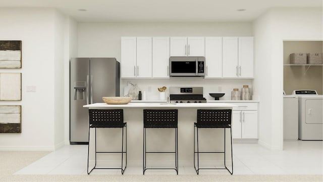 10436 NW Suncrest Loop, Port Saint Lucie, FL 34984 - kitchen with appliances with stainless steel finishes, independent washer and dryer, white cabinetry, a kitchen bar, and an island with sink