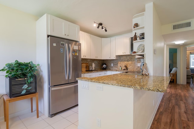 3000 Lake Osborne Dr Unit 103, Lake Worth Beach, FL 33461 - kitchen featuring freestanding refrigerator, open shelves, a peninsula, light stone counters, and white cabinetry