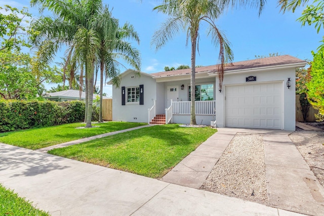305 Vanderbilt Dr, Lake Worth Beach, FL 33460 - view of front of house featuring stucco siding, concrete driveway, an attached garage, a front yard, and a porch
