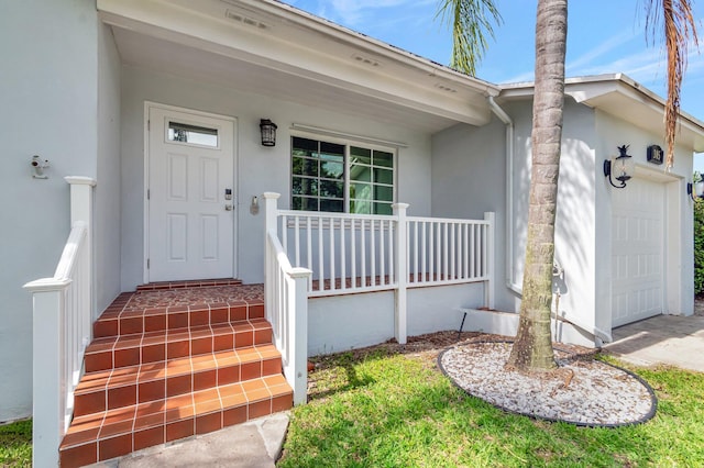 305 Vanderbilt Dr, Lake Worth Beach, FL 33460 - property entrance with stucco siding, an attached garage, and covered porch