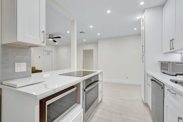 305 Vanderbilt Dr, Lake Worth Beach, FL 33460 - kitchen featuring appliances with stainless steel finishes, white cabinetry, light wood-style floors, light stone counters, and a ceiling fan
