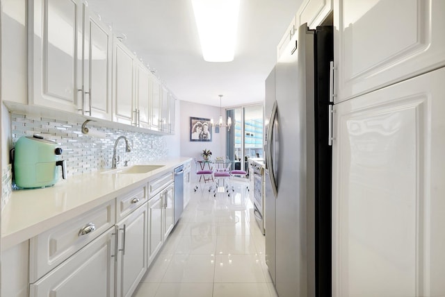 16711 Collins Ave Unit 1906, Sunny Isles Beach, FL 33160 - kitchen featuring stainless steel appliances, a sink, backsplash, light countertops, and white cabinetry