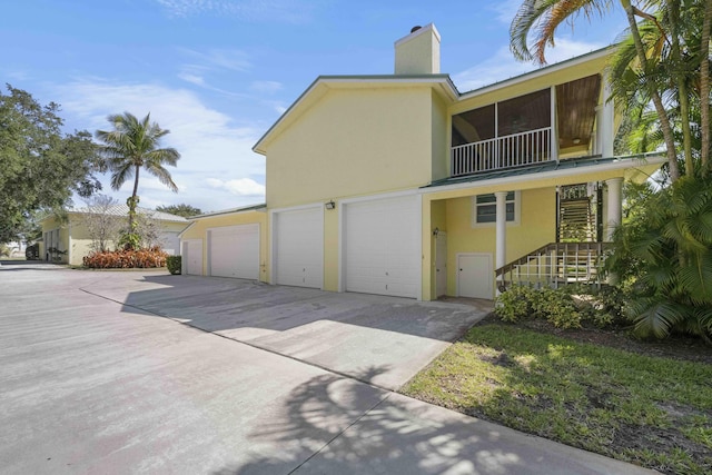 1530 NE Dixie Hwy, Jensen Beach, FL 34957 - view of front of property featuring stucco siding, concrete driveway, a chimney, stairs, and a garage