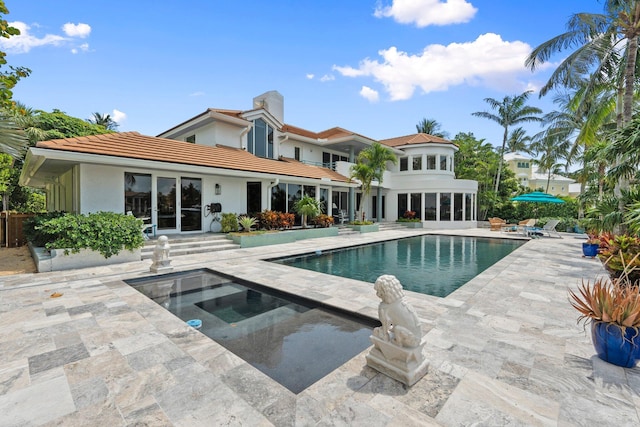 6460 SE Harbor Cir, Stuart, FL 34996 - back of house featuring a patio area, an in-ground hot tub, an outdoor pool, a tiled roof, and a chimney