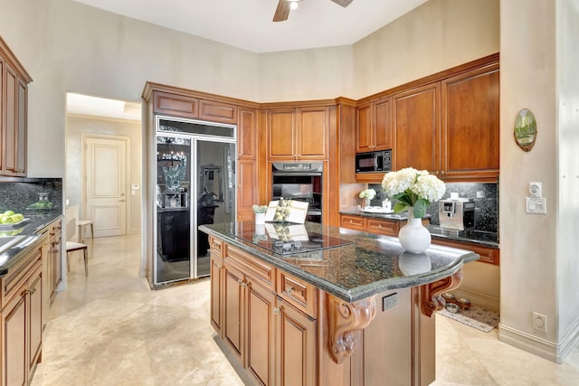 3628 S Ocean Blvd, Highland Beach, FL 33487 - kitchen with black appliances, decorative backsplash, a ceiling fan, a center island, and dark stone countertops