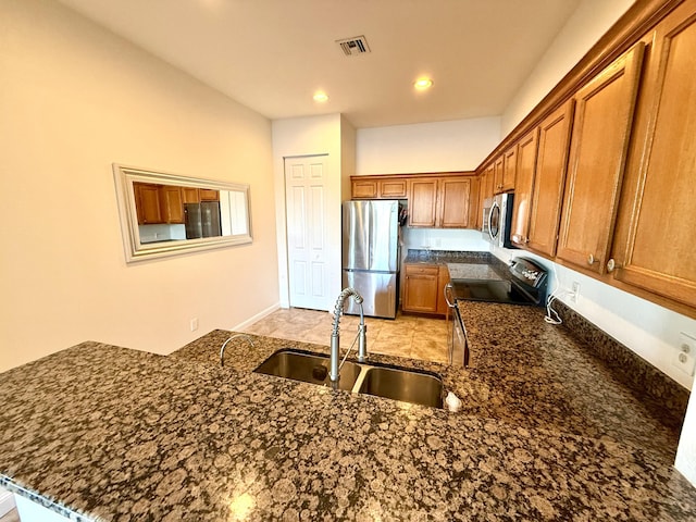 855 Marina Del Ray Ln Unit 2, West Palm Beach, FL 33401 - kitchen featuring appliances with stainless steel finishes, a sink, brown cabinets, dark stone counters, and recessed lighting