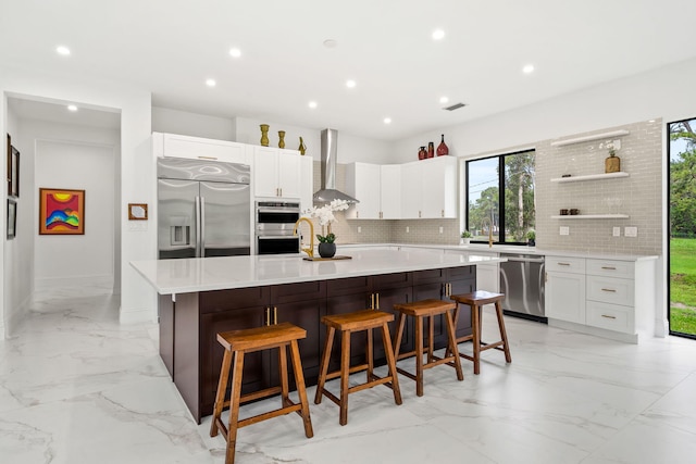 7887 150th Ct N, Palm Beach Gardens, FL 33418 - kitchen with appliances with stainless steel finishes, wall chimney range hood, light marble finish floors, decorative backsplash, and recessed lighting