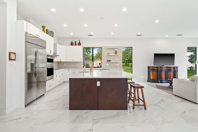 7887 150th Ct N, Palm Beach Gardens, FL 33418 - kitchen featuring stainless steel appliances, open floor plan, an island with sink, tasteful backsplash, and light countertops