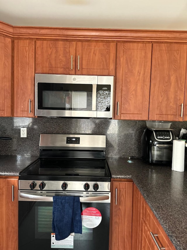519 NW 3rd Ave Unit 519-521, Hallandale Beach, FL 33009 - kitchen featuring appliances with stainless steel finishes, brown cabinetry, tasteful backsplash, and dark stone counters