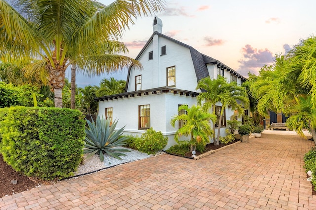 230 Princeton Dr, Lake Worth Beach, FL 33460 - property exterior at dusk with stucco siding and a chimney