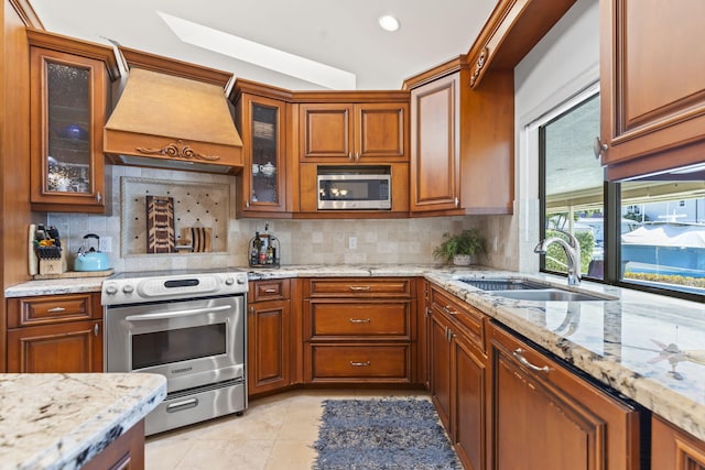 3819 N Ocean Dr, Singer Island, FL 33404 - kitchen with appliances with stainless steel finishes, a sink, premium range hood, brown cabinetry, and tasteful backsplash