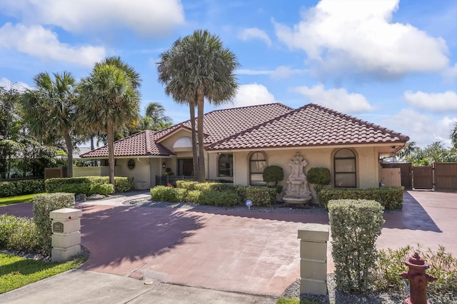 3819 N Ocean Dr, Singer Island, FL 33404 - mediterranean / spanish-style house featuring a gate, a tile roof, stucco siding, and driveway