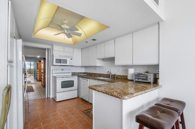 1900 Consulate Pl Unit 402, West Palm Beach, FL 33401 - kitchen with white appliances, a peninsula, white cabinets, a sink, and ceiling fan