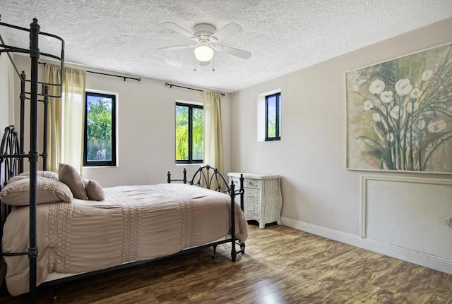880 NE Stokes Ter, Jensen Beach, FL 34957 - bedroom with baseboards, wood finished floors, a textured ceiling, and ceiling fan