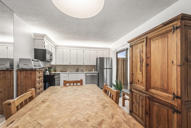 2513 25th Ln, Palm Beach Gardens, FL 33418 - kitchen featuring stainless steel appliances, a sink, a textured ceiling, and white cabinets