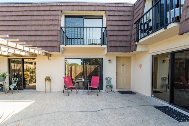 2513 25th Ln, Palm Beach Gardens, FL 33418 - entrance to property with mansard roof, stucco siding, a balcony, and a patio