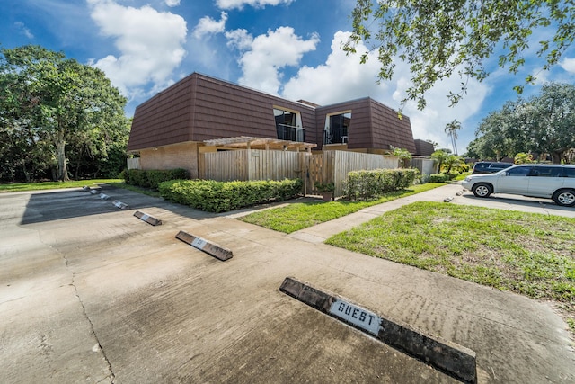 2513 25th Ln, Palm Beach Gardens, FL 33418 - exterior space with mansard roof, brick siding, and uncovered parking