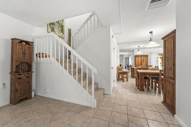 2513 25th Ln, Palm Beach Gardens, FL 33418 - stairs with a textured ceiling, baseboards, and stone tile flooring