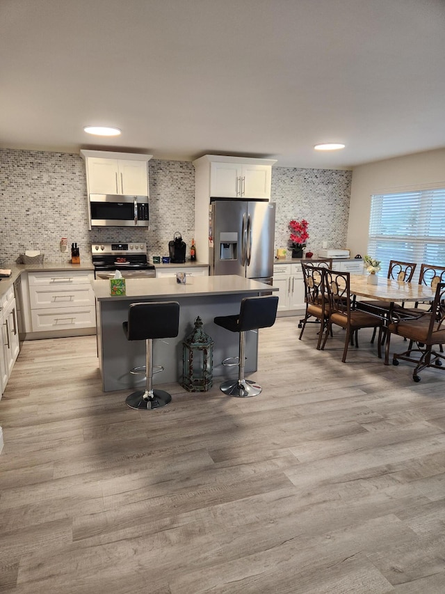 302 Wellington Unit B, West Palm Beach, FL 33417 - kitchen with stainless steel appliances, decorative backsplash, a kitchen island, white cabinets, and recessed lighting