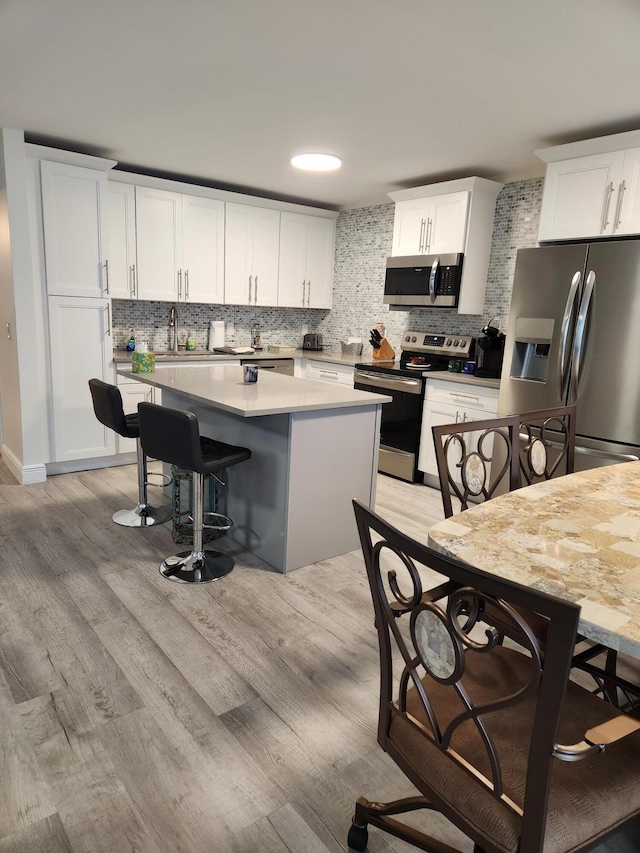 302 Wellington Unit B, West Palm Beach, FL 33417 - kitchen with appliances with stainless steel finishes, a center island, backsplash, and light wood finished floors