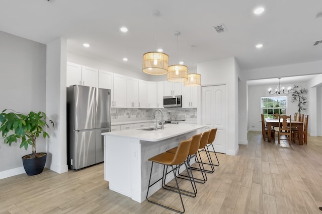3974 SW Jarmer Rd, Port Saint Lucie, FL 34953 - kitchen featuring appliances with stainless steel finishes, light wood-type flooring, light countertops, backsplash, and a sink