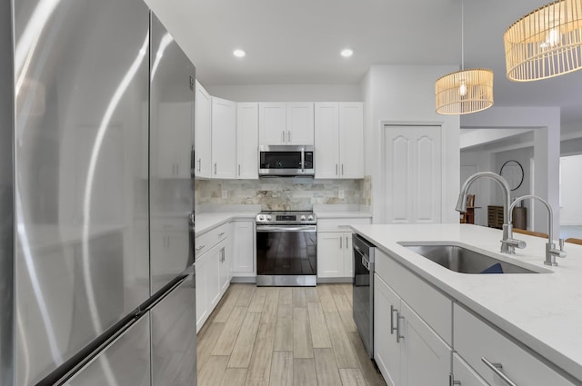 3974 SW Jarmer Rd, Port Saint Lucie, FL 34953 - kitchen featuring stainless steel appliances, a sink, backsplash, white cabinets, and light wood-type flooring