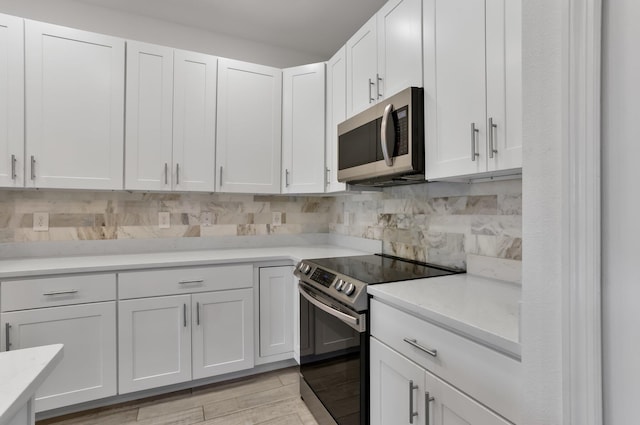 3974 SW Jarmer Rd, Port Saint Lucie, FL 34953 - kitchen featuring appliances with stainless steel finishes, light countertops, backsplash, and white cabinets