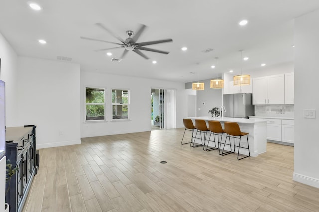 3974 SW Jarmer Rd, Port Saint Lucie, FL 34953 - kitchen with freestanding refrigerator, open floor plan, ceiling fan, a kitchen bar, and a center island with sink