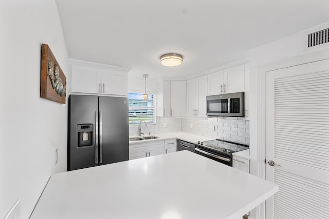 109 Wettaw Ln Unit 103, North Palm Beach, FL 33408 - kitchen with appliances with stainless steel finishes, a sink, backsplash, light countertops, and white cabinets