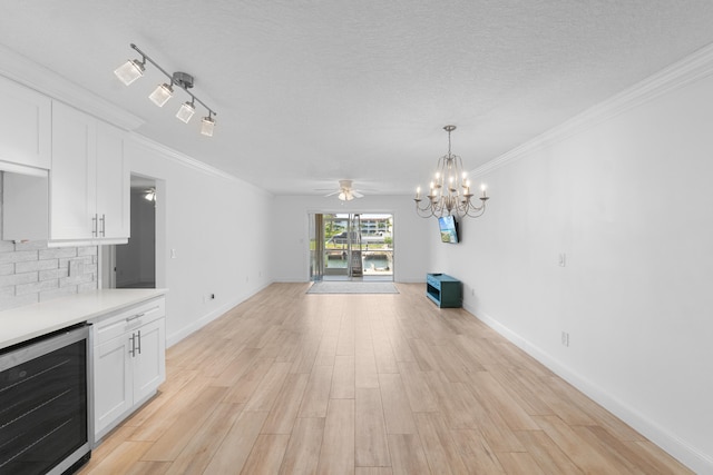 109 Wettaw Ln Unit 103, North Palm Beach, FL 33408 - unfurnished living room featuring beverage cooler, light wood-style floors, a chandelier, crown molding, and a textured ceiling