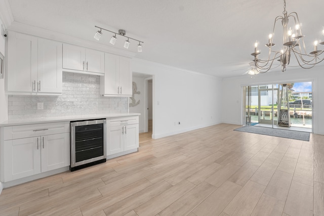 109 Wettaw Ln Unit 103, North Palm Beach, FL 33408 - kitchen with beverage cooler, a chandelier, light countertops, white cabinets, and tasteful backsplash