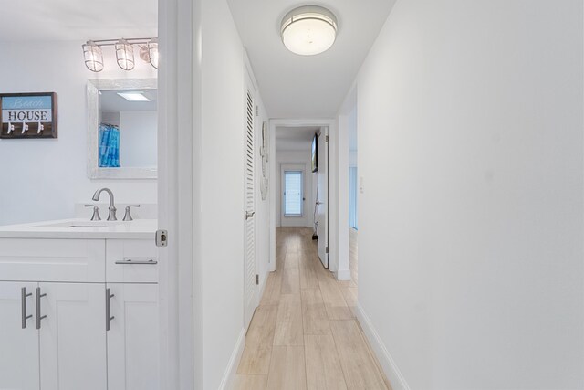 109 Wettaw Ln Unit 103, North Palm Beach, FL 33408 - hallway with a sink, baseboards, and light wood-style flooring