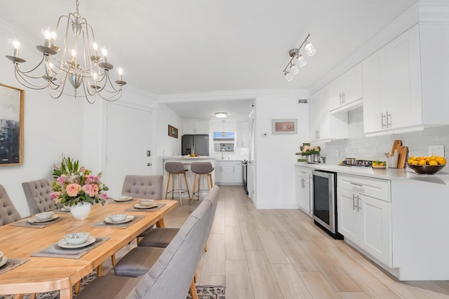 109 Wettaw Ln Unit 103, North Palm Beach, FL 33408 - dining room featuring beverage cooler, a chandelier, light wood-style flooring, and ornamental molding