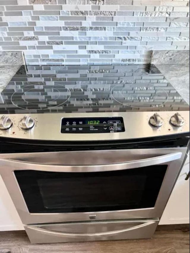 343 SE Husted Ter, Port Saint Lucie, FL 34983 - kitchen view of decorative backsplash, stainless steel range with electric cooktop, dark wood-type flooring, and white cabinetry