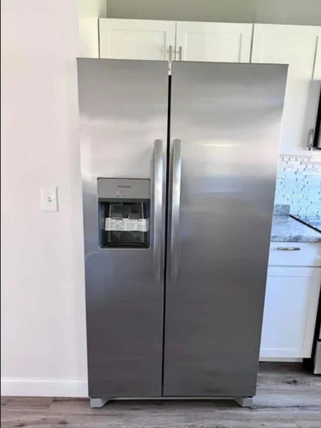 343 SE Husted Ter, Port Saint Lucie, FL 34983 - kitchen view of stainless steel fridge with ice dispenser, white cabinets, light wood finished floors, baseboards, and light stone countertops