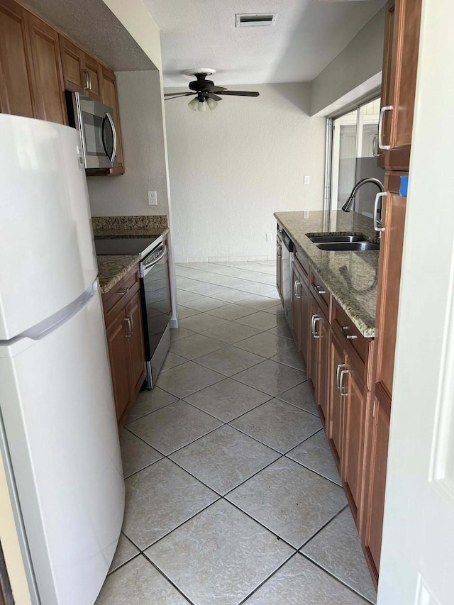 318 NW Byron St, Port Saint Lucie, FL 34983 - kitchen featuring freestanding refrigerator, stainless steel microwave, a sink, range with electric cooktop, and dark stone countertops