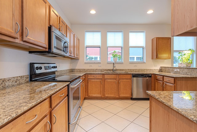433 Amador Ln Unit 1, West Palm Beach, FL 33401 - kitchen with stainless steel appliances, a sink, light tile patterned flooring, light stone countertops, and brown cabinetry