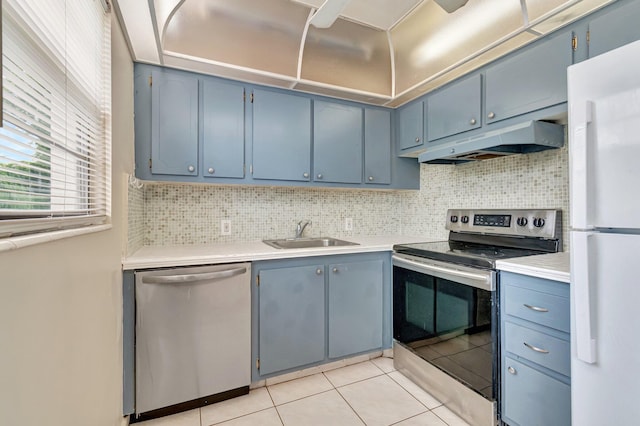 393 Fanshaw J, Boca Raton, FL 33434 - kitchen featuring appliances with stainless steel finishes, under cabinet range hood, a sink, blue cabinets, and backsplash